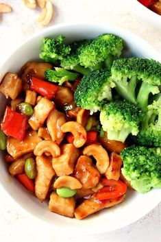 a bowl filled with broccoli, cashews and other food on top of a table