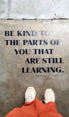 someone is standing in front of a sign that says be kind to the parts of you that are still learning