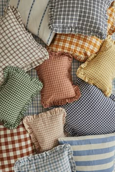 many pillows are arranged on top of each other in different colors and patterns, including checkered