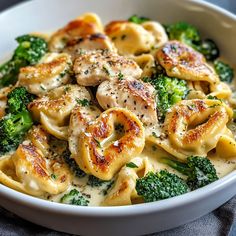 a white bowl filled with pasta and broccoli covered in cheese sauce on top of a blue cloth