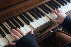 two hands are playing the piano with black and white keys, while another hand is holding on to it