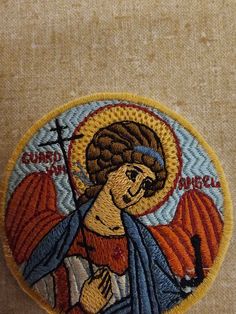 an image of jesus holding the cross in his hands embroidered onto a tan fabric background