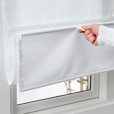 a person is opening the window with their hand and pulling it out from under the blinds