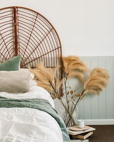 a bed with white sheets and pillows next to a bamboo headboard on the wall