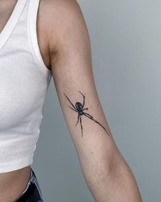 a woman's arm with a spider tattoo on the back of her left arm