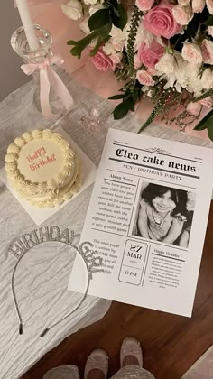 a table topped with a cake next to a bouquet of flowers and a piece of paper