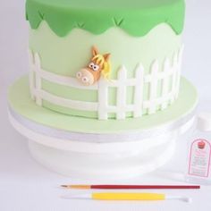 a green cake with a horse on it and some crayons next to it