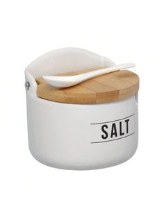 a wooden spoon sitting on top of a white container with the word salt written on it