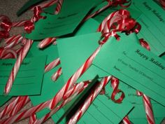 candy canes are wrapped in green paper with red and white ribbons around them on the floor