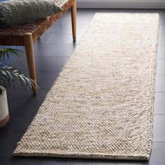 a white rug is on the floor in front of a chair and potted plant