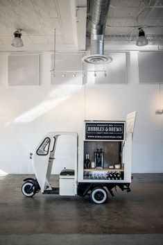 a small cart is parked in the middle of an empty room with white walls and exposed ceilings