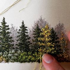 someone is stitching trees on the back of a piece of fabric with yellow and green thread