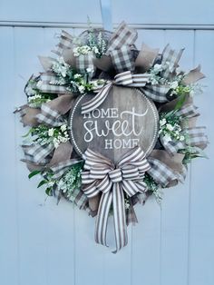 a wreath that says home sweet home on the front door with flowers and ribbon around it