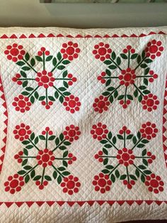 a white quilt with red and green flowers on it