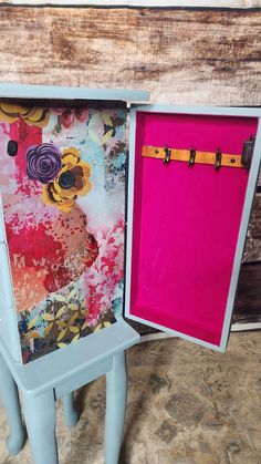 an open box sitting on top of a wooden table next to a stool with flowers painted on it