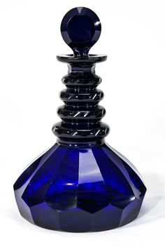 a blue glass bottle sitting on top of a white table next to a black object