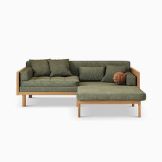 a green couch with pillows on it and a footstool in front of it