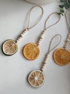 three orange slices hanging from strings on a white surface