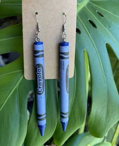 two blue crayons are hanging from earrings