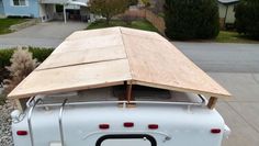 an old white truck with a wooden roof on the back in front of a house