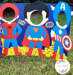 a wooden sign with superheros painted on it and a frisbee in the grass