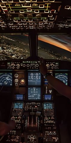 two pilots in the cockpit of an airplane looking at their screens and landing gear as they fly through the night sky