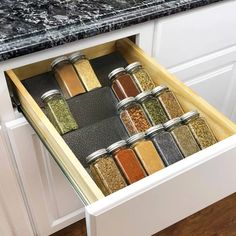 an open drawer in a kitchen filled with spices and seasonings on the counter top