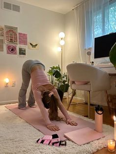 a woman is doing yoga on the floor in front of a computer desk with candles