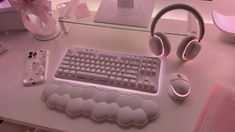 a computer desk with headphones, keyboard and mouse on it in front of a pink background