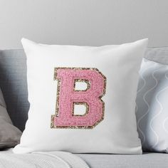 the letter b is made up of pink and gold sequins on a white pillow