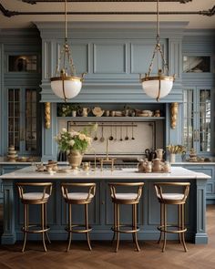 a kitchen with blue cabinets and marble counter tops, gold bar stools and brass accents