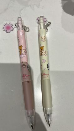 two pens sitting next to each other on top of a white table with pink flowers