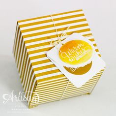 a yellow and white striped gift box with a tag on the top that says merry christmas