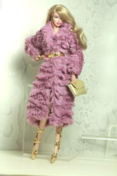 a barbie doll is dressed in a pink fur coat and matching heels, holding a purse