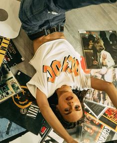 a man laying on the ground with his head down in front of some cds and magazines