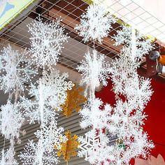 snow flakes hanging from the ceiling in front of a red wall with white writing on it