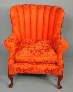 an orange upholstered chair sitting on top of a gray floor