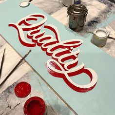 a sign that says coca cola on it with paint and brushes in front of it