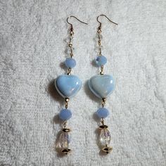 two heart shaped glass beads are hanging from gold earwires on a white sheet