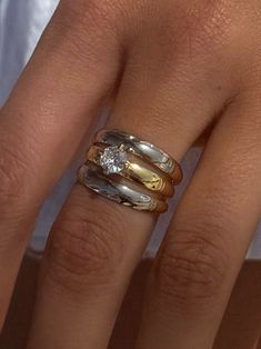 a woman's hand with three different rings on her fingers and one has a diamond in the middle