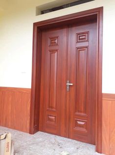 two wooden doors in front of a white wall and some bags on the ground next to them