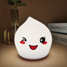 a close up of a white object on a table with books and a plant in the background