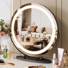 a round mirror sitting on top of a table next to a vase with flowers in it