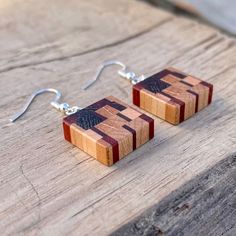 wooden earrings with silver earwires are on a wood table and have been made to look like squares or rectangles