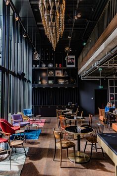 the interior of a restaurant with tables and chairs, hanging chandeliers and bookshelves