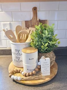 a wooden tray holding utensils, spoons and a potted plant