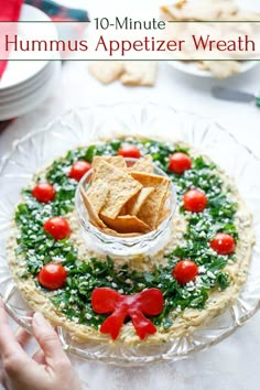 hummus appetizer wreath on a plate with crackers and tomatoes in it