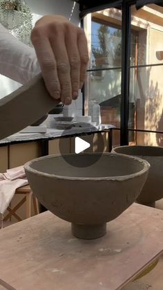 a person is making a bowl out of clay