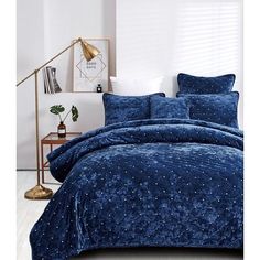 a blue comforter set with stars on it in a white room next to a lamp