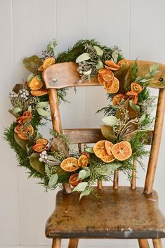 an old wooden chair with a wreath on the back and oranges attached to it